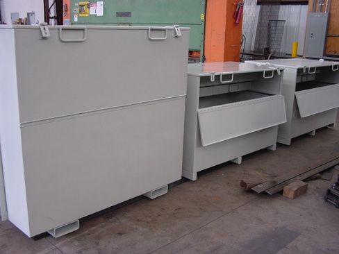 A row of white boxes with handles are sitting on a concrete floor.