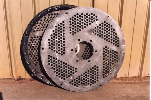 Two metal plates with holes in them are stacked on top of each other