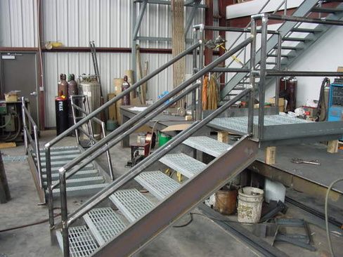 A metal staircase is being built in a factory