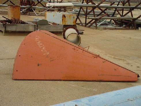 A large piece of red metal is sitting on the ground.