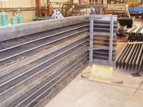 A large stack of metal pipes in a factory.