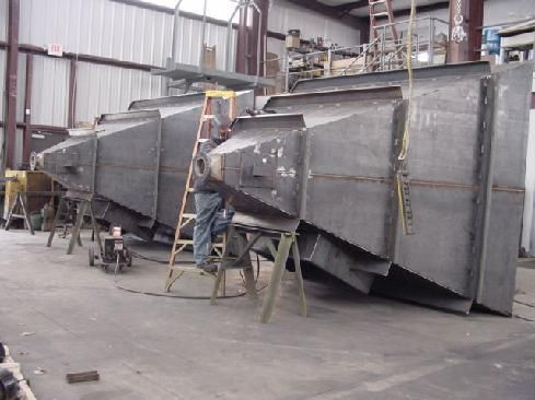 A man is working on a large piece of metal in a factory.