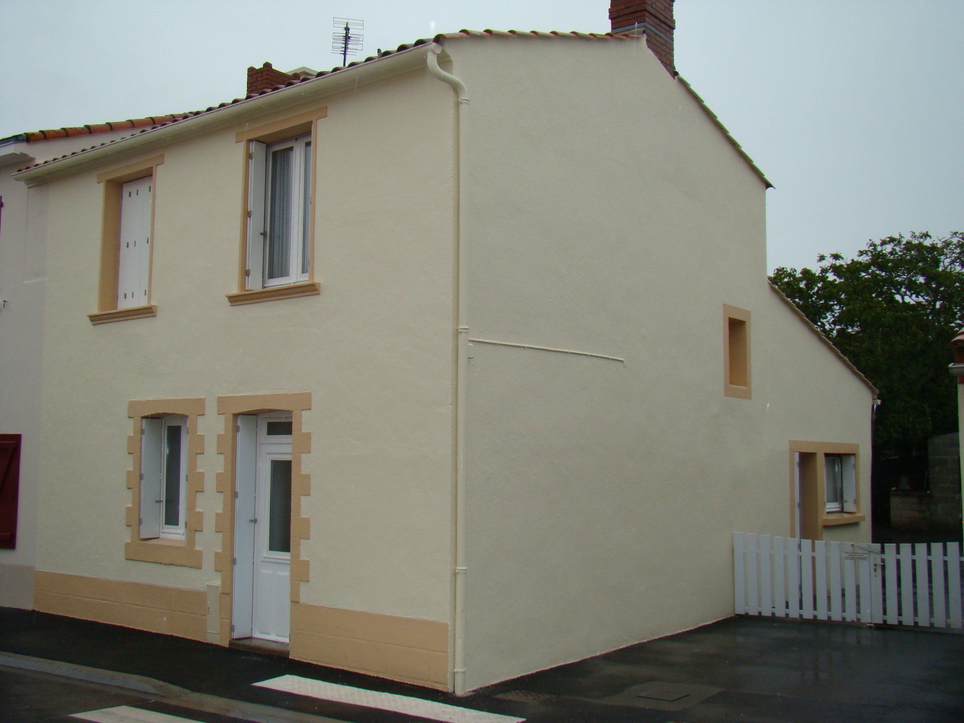 Une maison blanche avec une clôture blanche devant