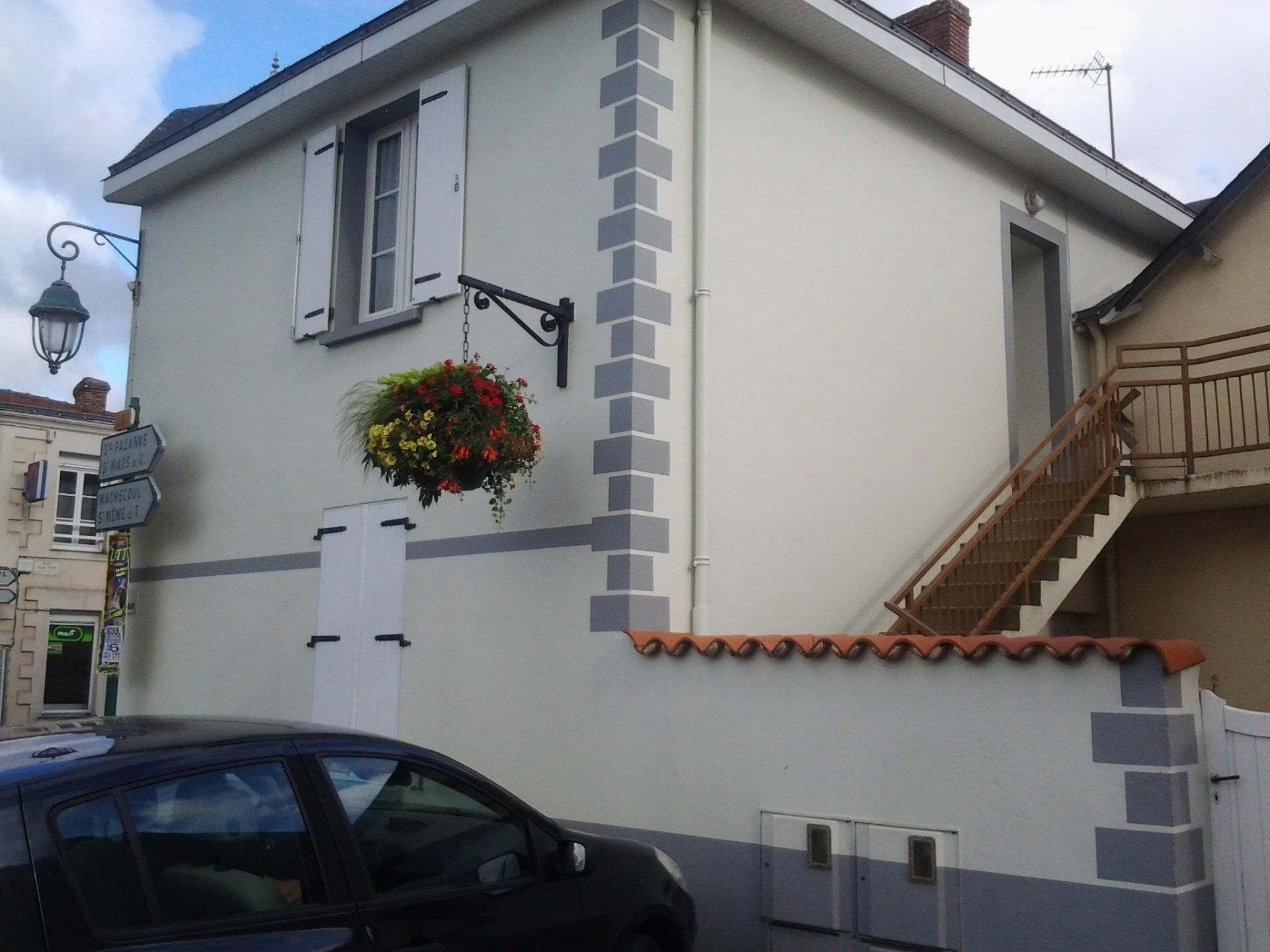 Une voiture est garée devant une maison blanche