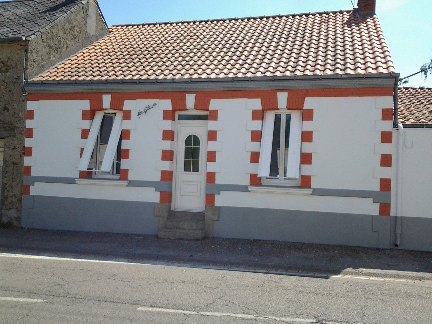 Une maison blanche et orange avec un toit de tuiles