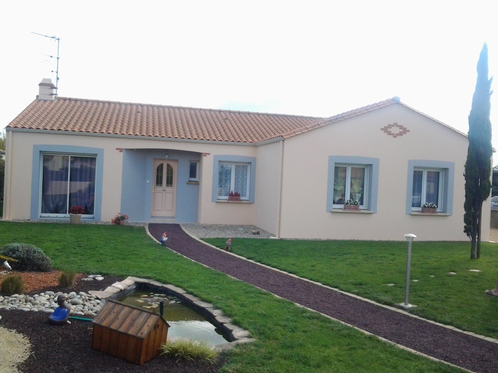 Une maison avec une passerelle et un étang devant