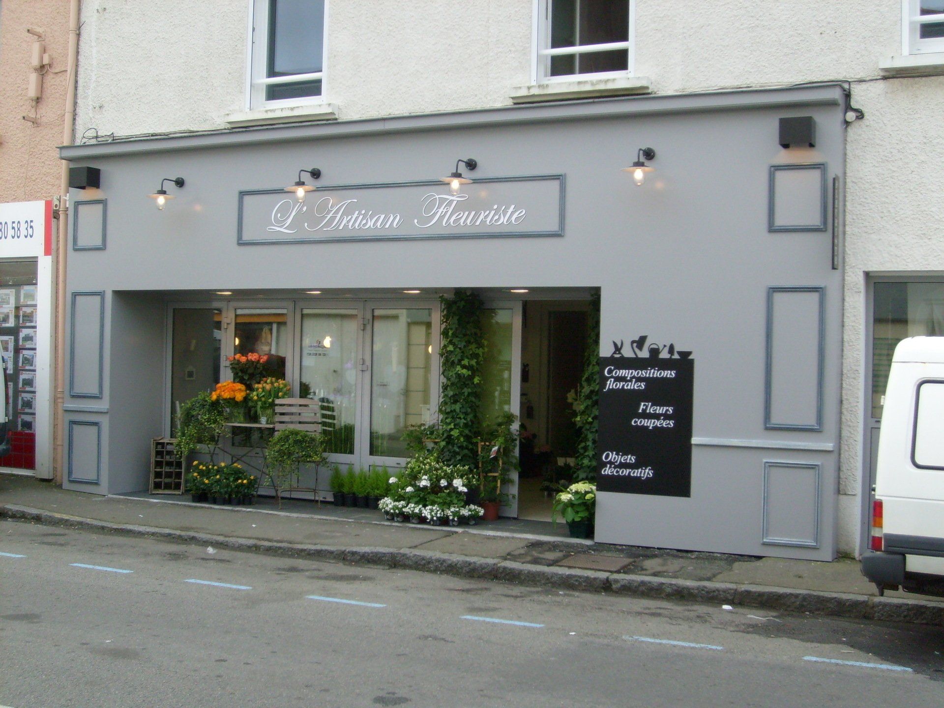 Une camionnette blanche est garée devant un magasin appelé l'artisan fleuriste