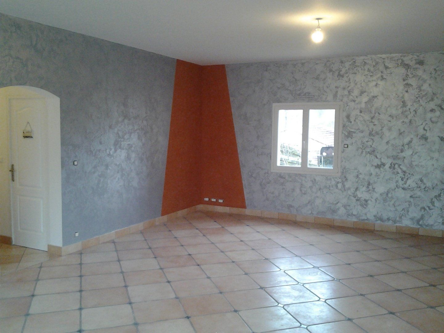 Un salon vide avec un sol carrelé et une fenêtre.