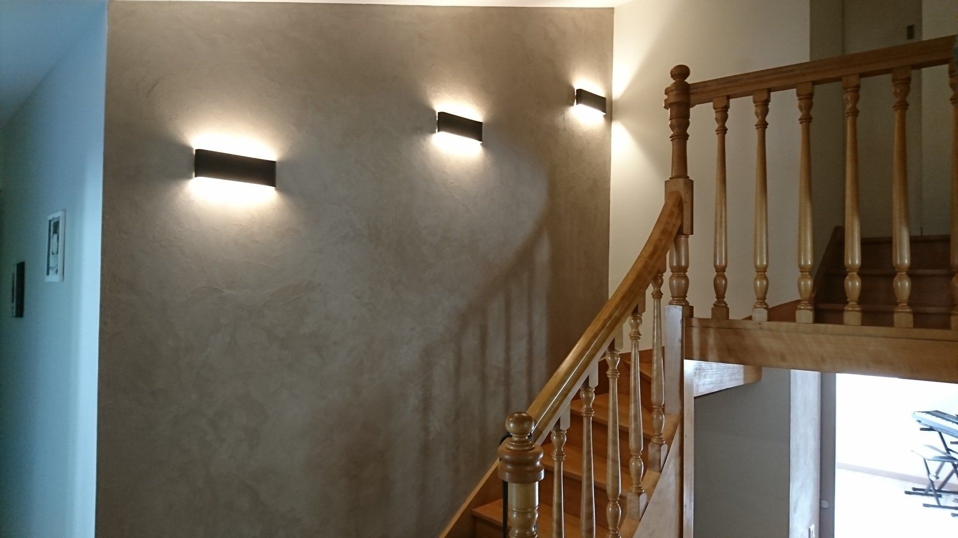 Un escalier en bois avec des lumières sur le mur derrière lui