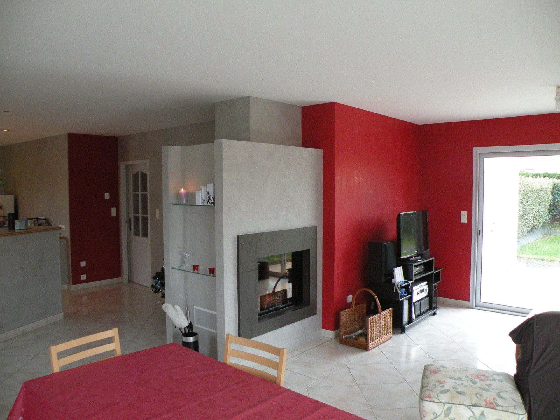 Un salon avec des murs rouges et une cheminée