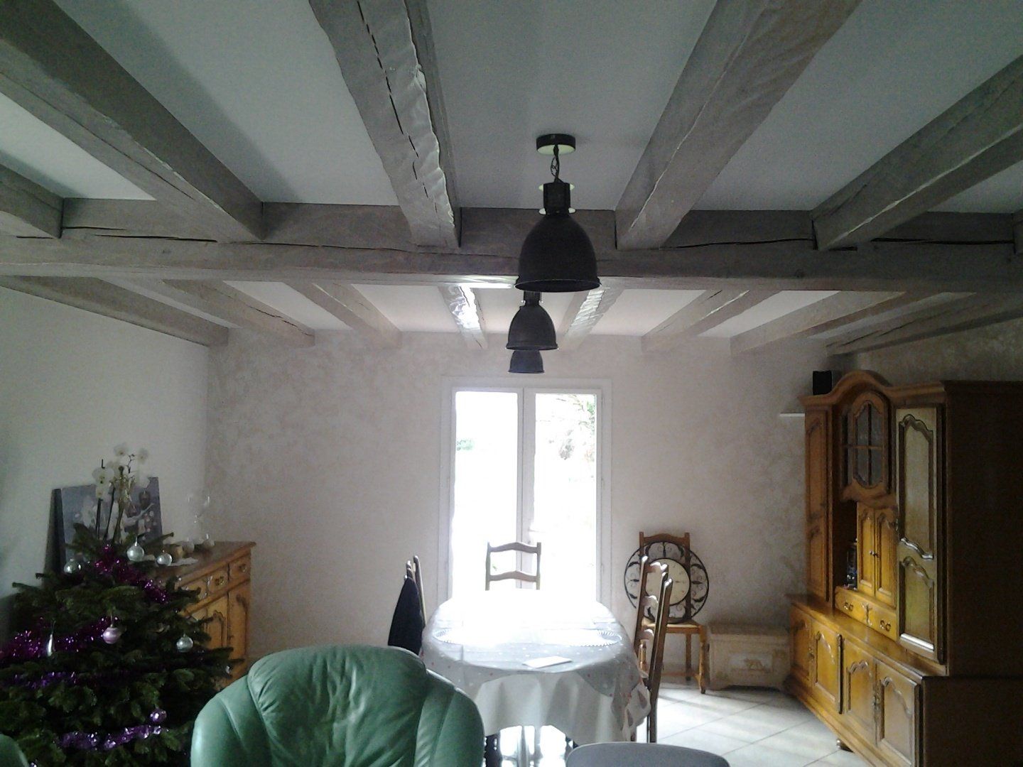 Un salon avec une table et des chaises et un sapin de Noël