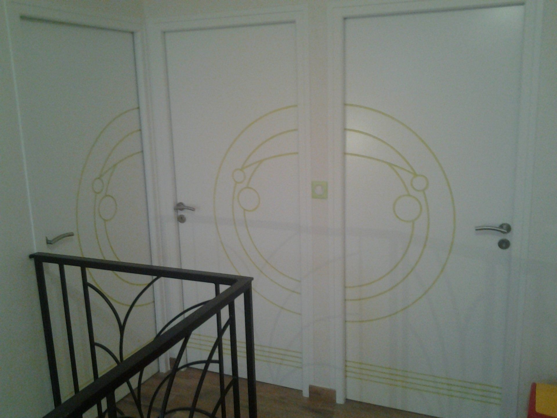 Un escalier avec des portes blanches et une rampe noire