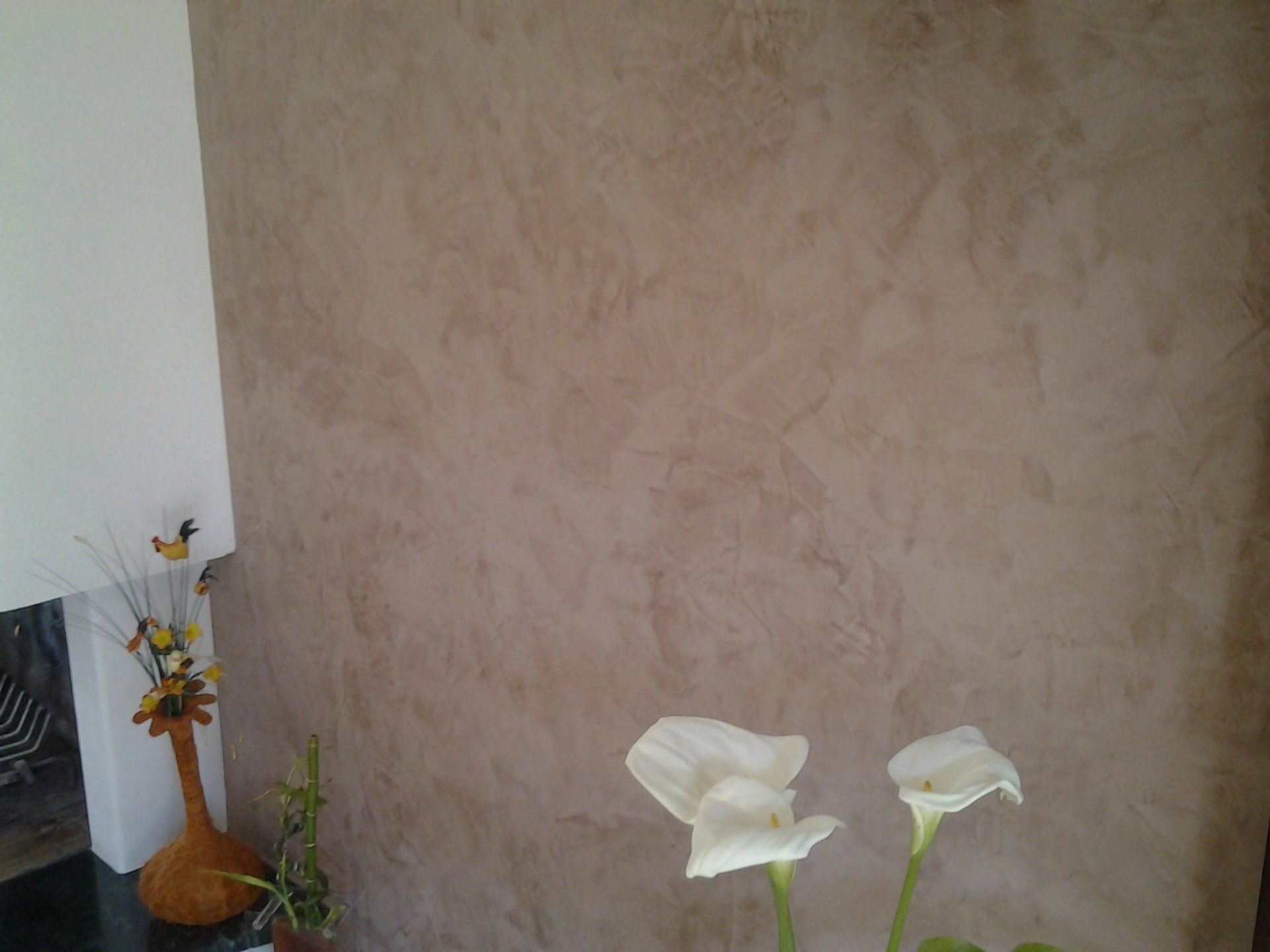 Un vase de fleurs est posé sur une table devant un mur.