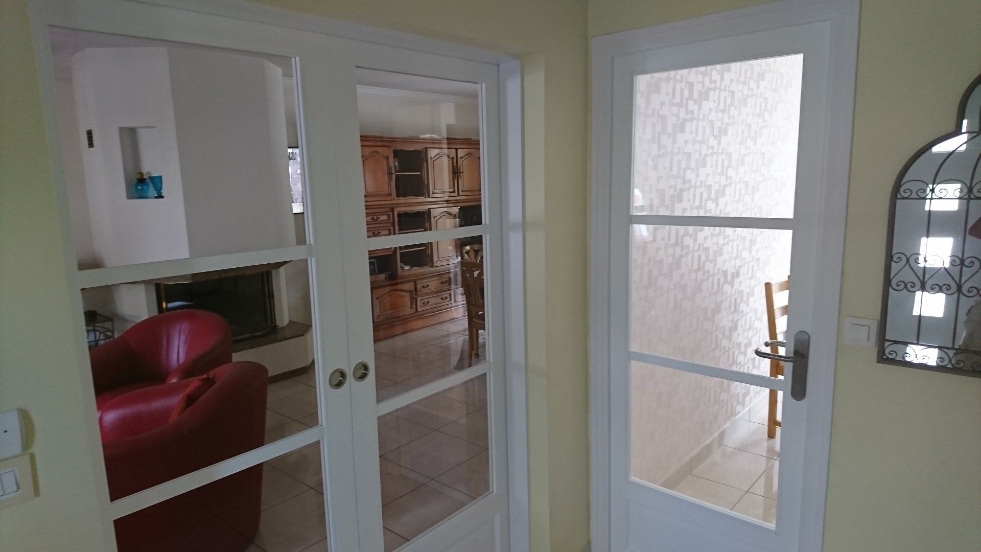 Un salon avec des portes coulissantes en verre et une chaise rouge.