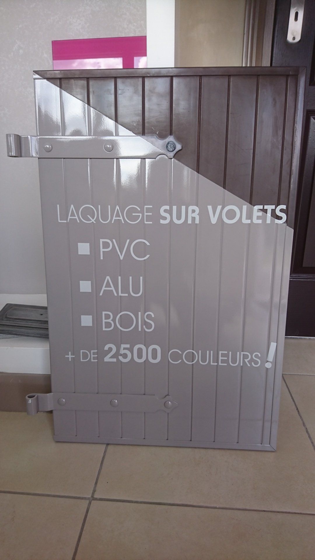 Une porte en bois repose sur un sol carrelé.