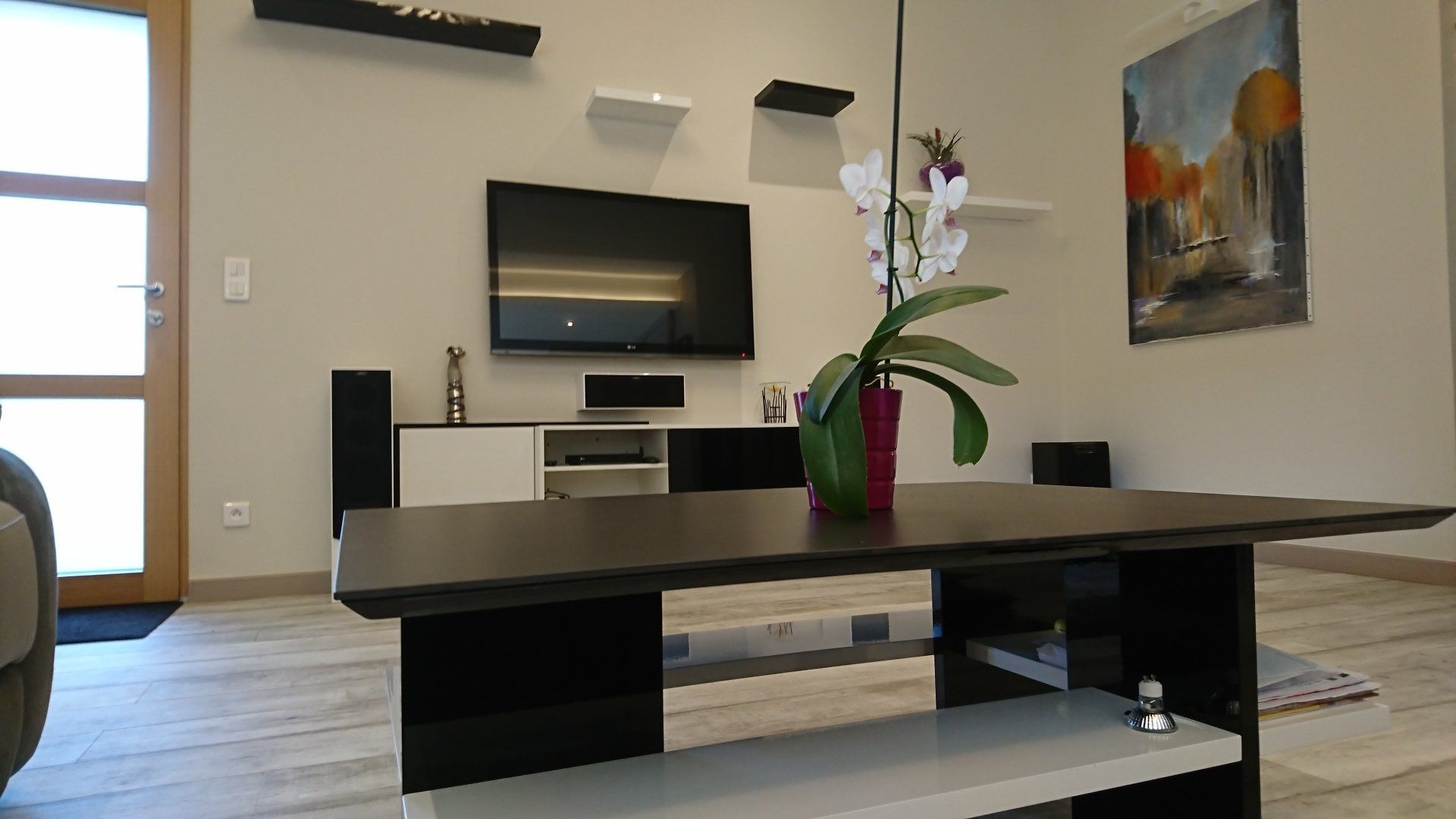 Un salon avec une table basse et une télé au mur.