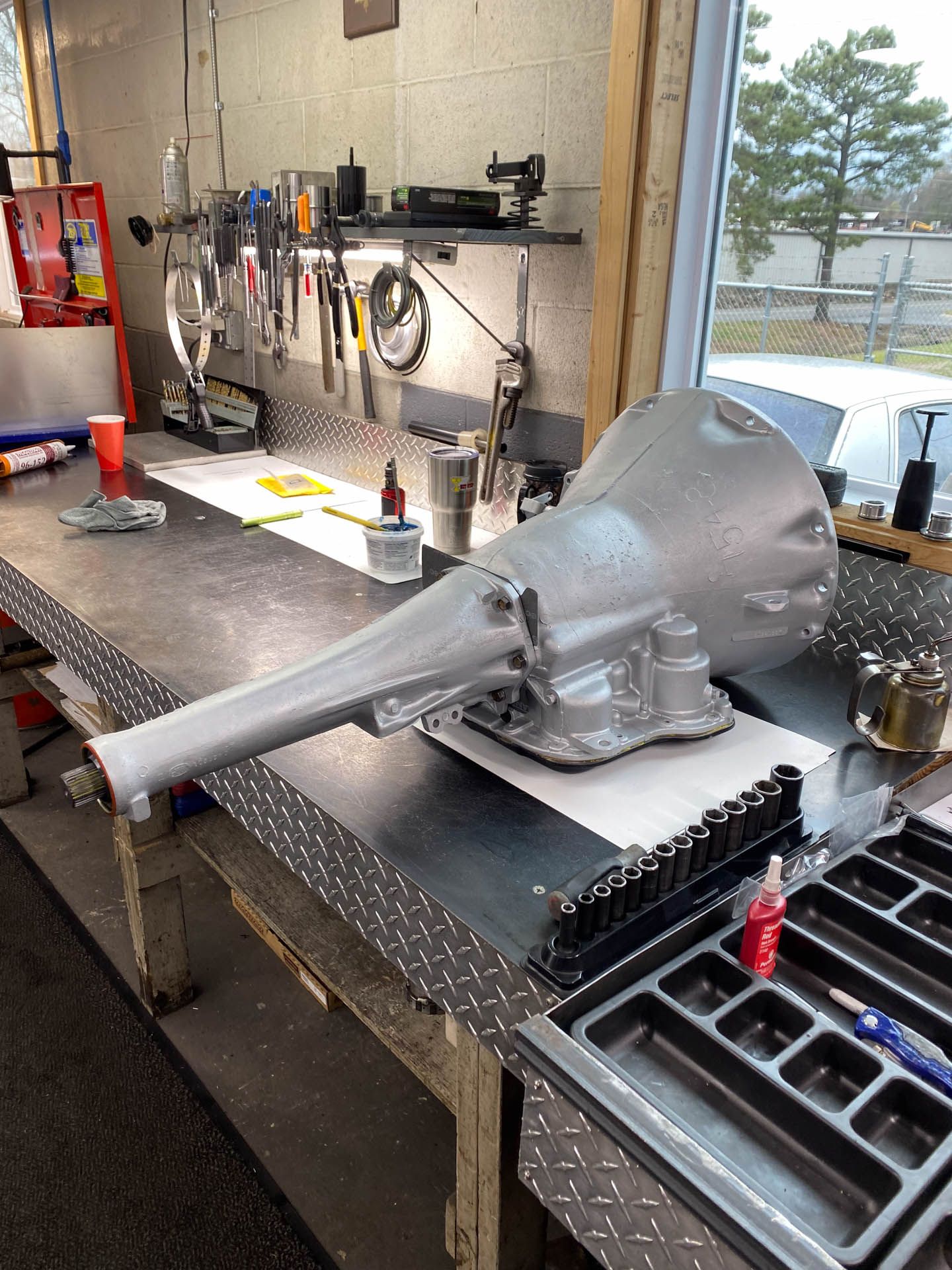 A transmission is sitting on a table in a garage.