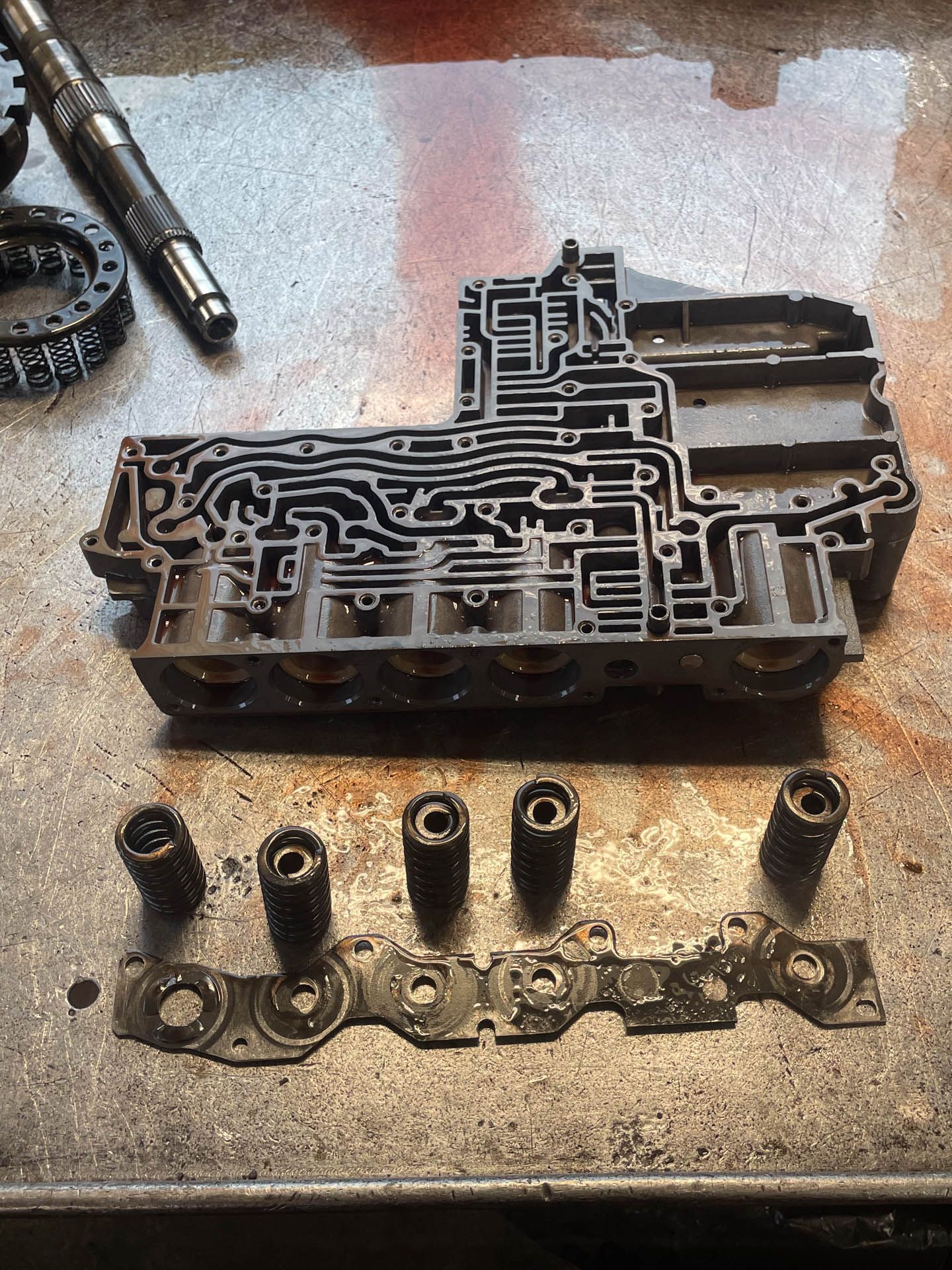 A piece of metal is sitting on a table next to a pen.