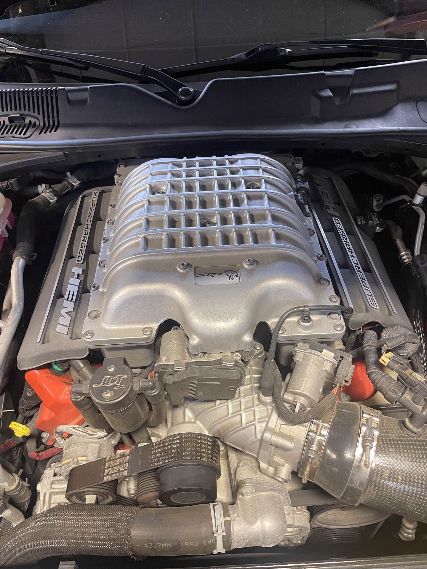 A close up of a car engine with a hood open.