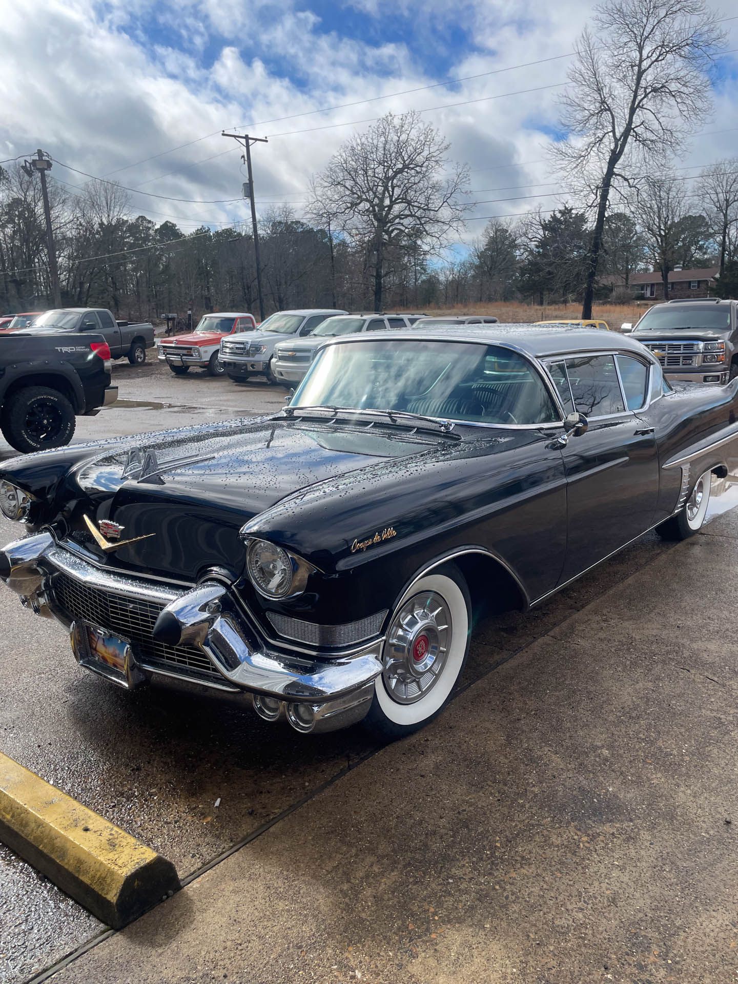 A black cadillac is parked in a parking lot.