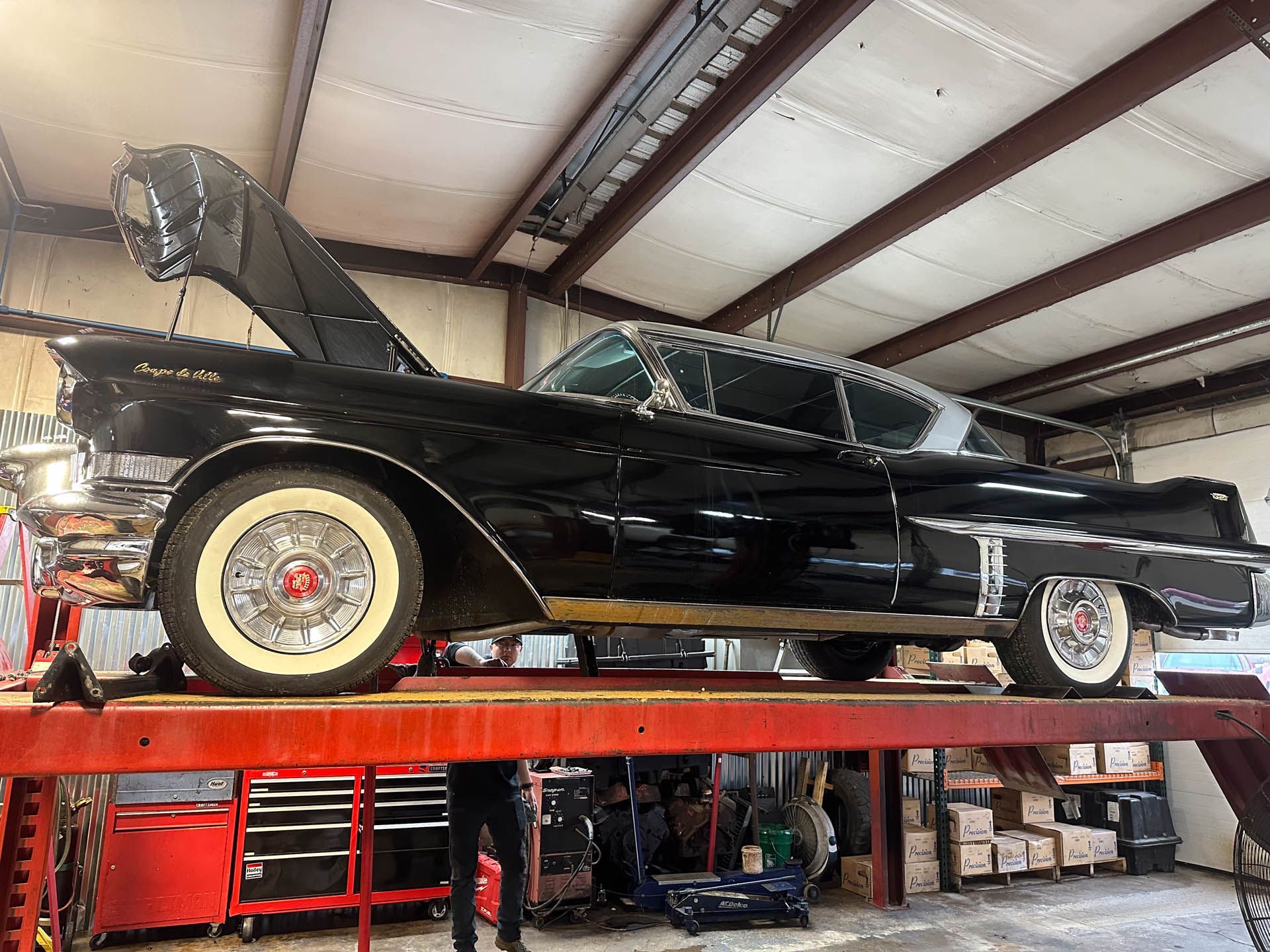 A black car is sitting on top of a red lift in a garage.