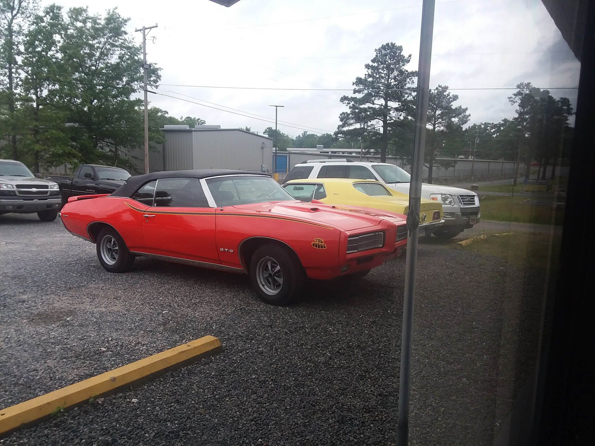 A red convertible car is parked in a parking lot