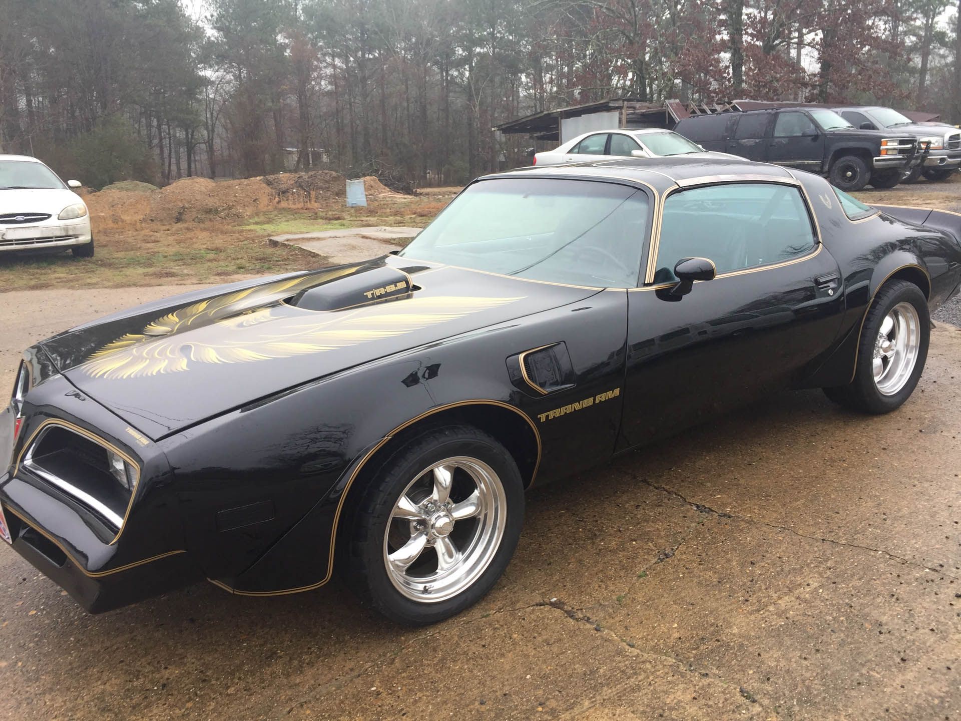A black and gold muscle car is parked on the side of the road.