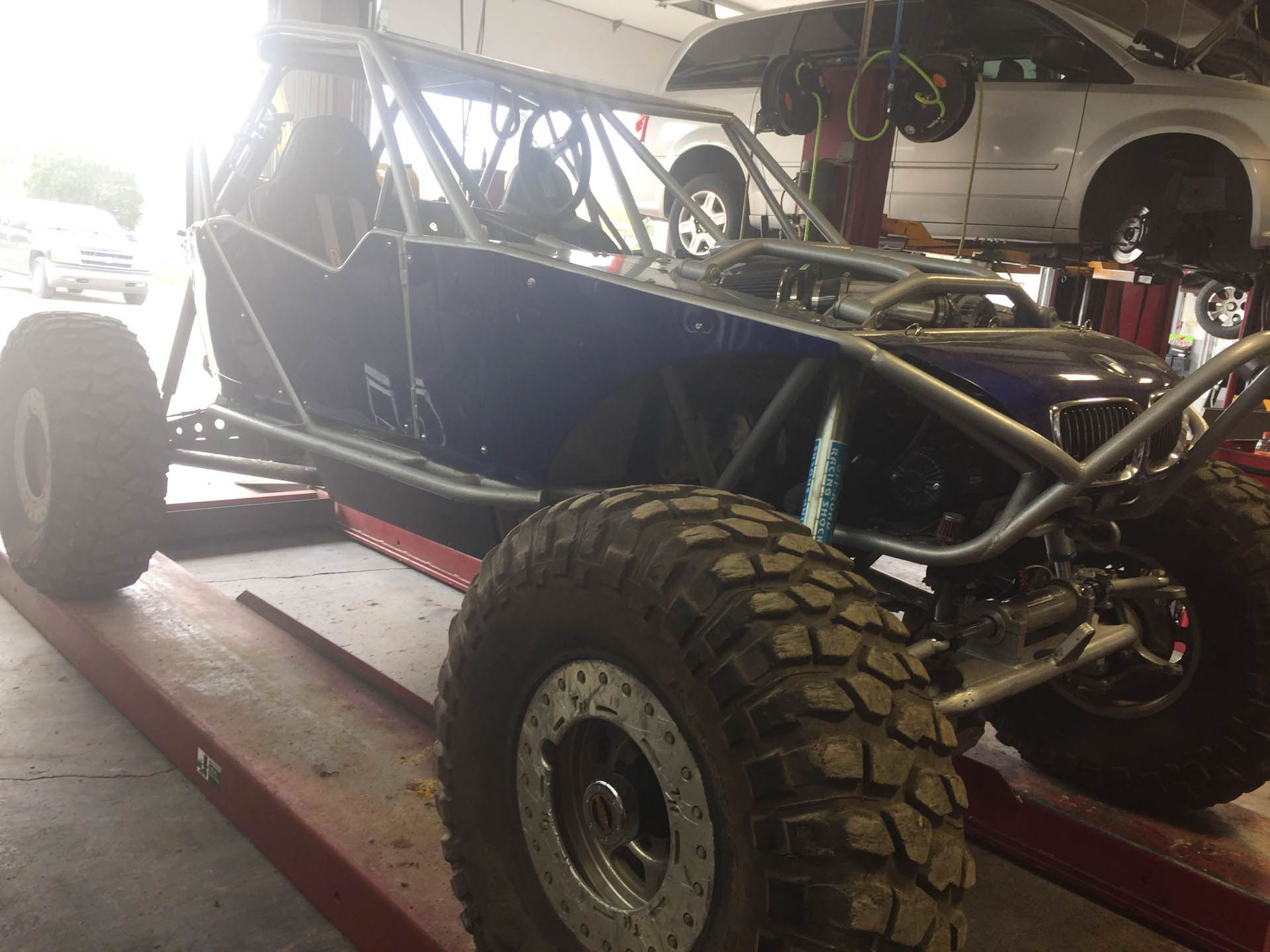 A buggy is sitting on a lift in a garage.