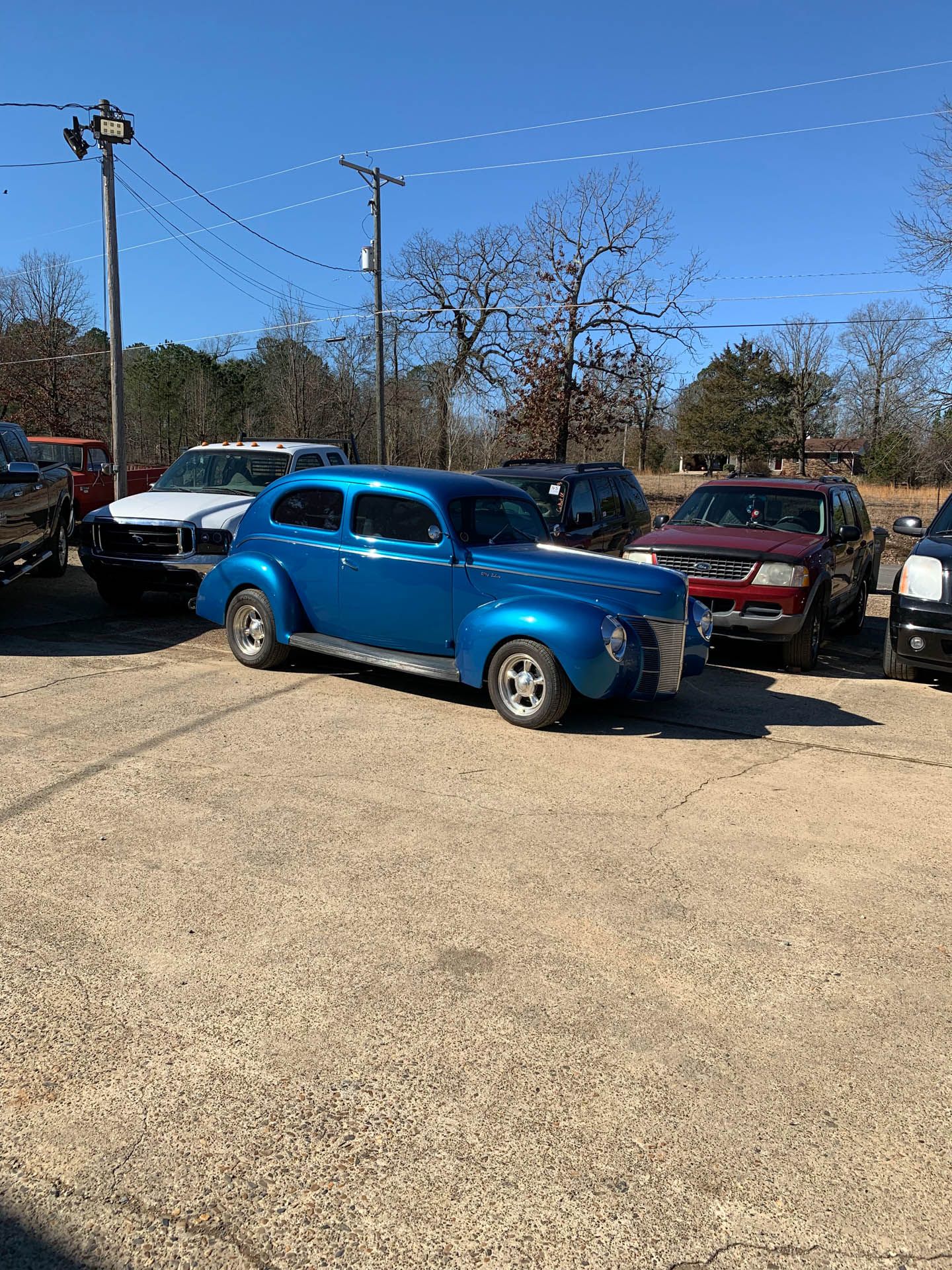 A blue car is parked in a parking lot next to other cars.