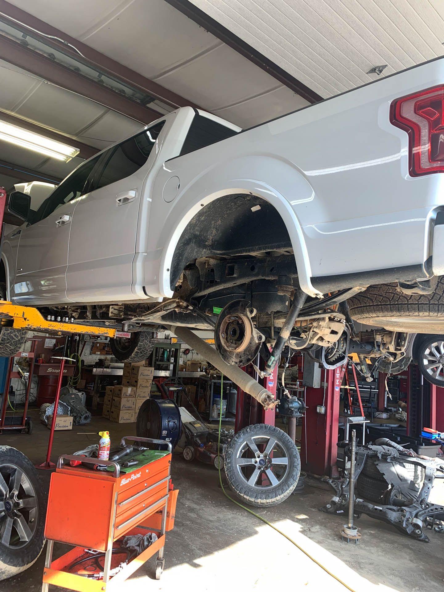 A white truck is sitting on a lift in a garage.