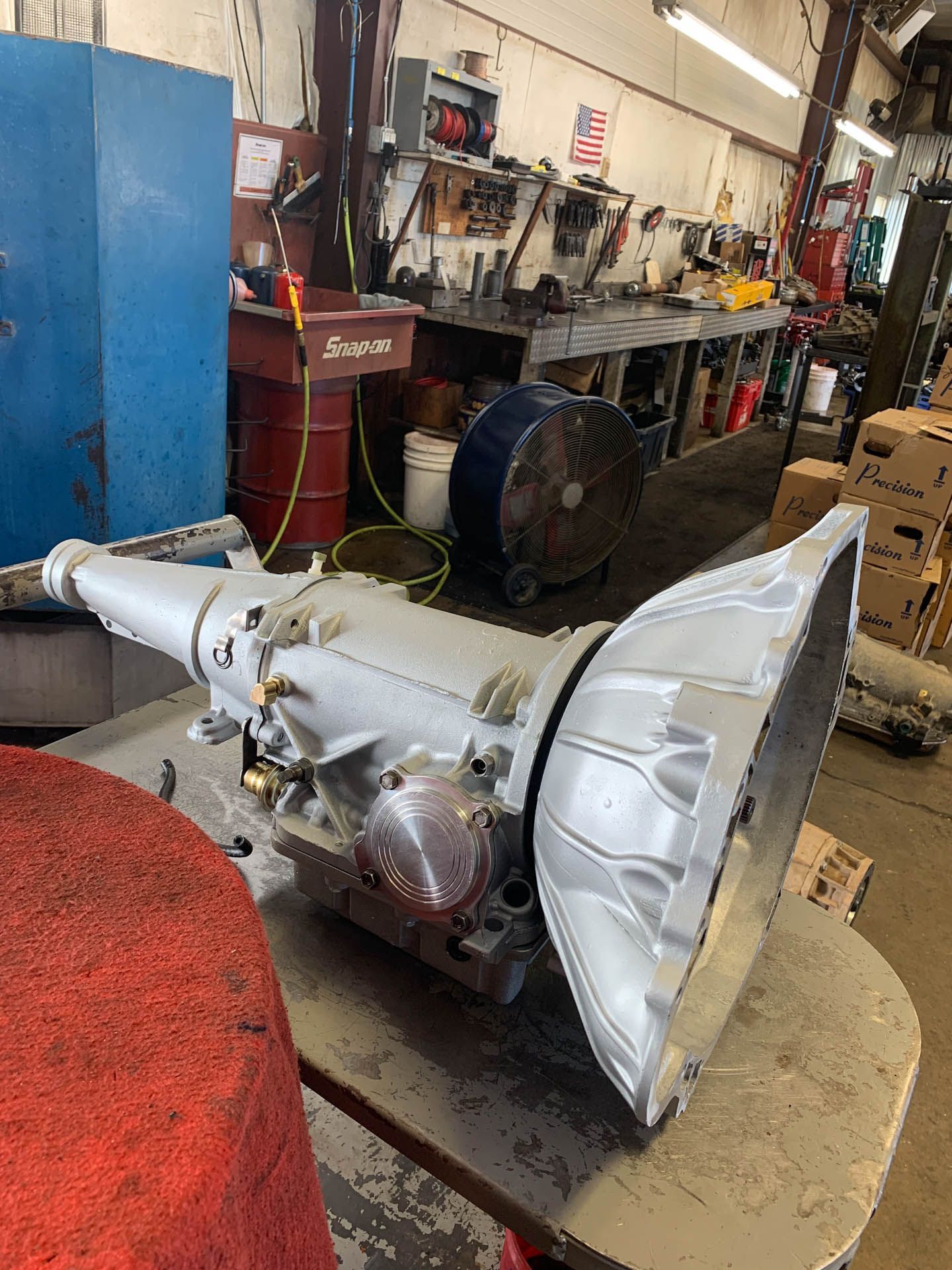A transmission is sitting on a table in a garage.