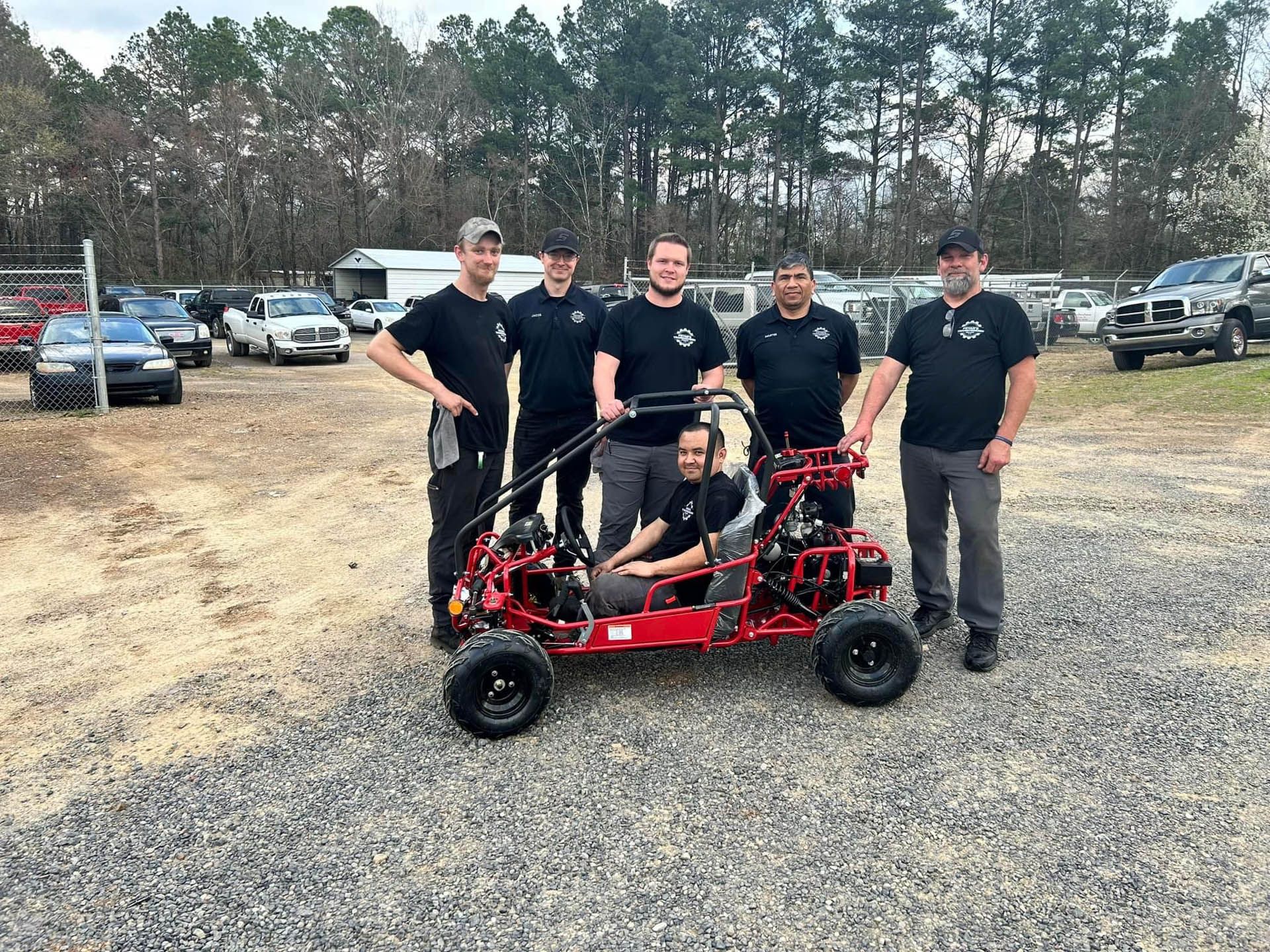A group of men are standing around a red buggy.