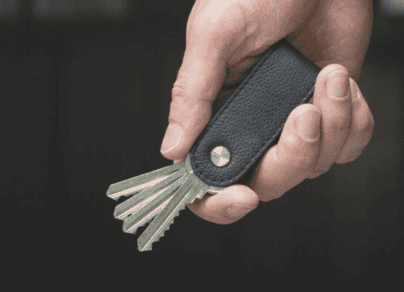 A person is holding a key holder with keys in it.