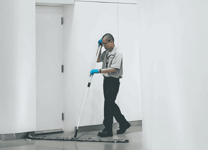 A man is cleaning the floor with a mop.