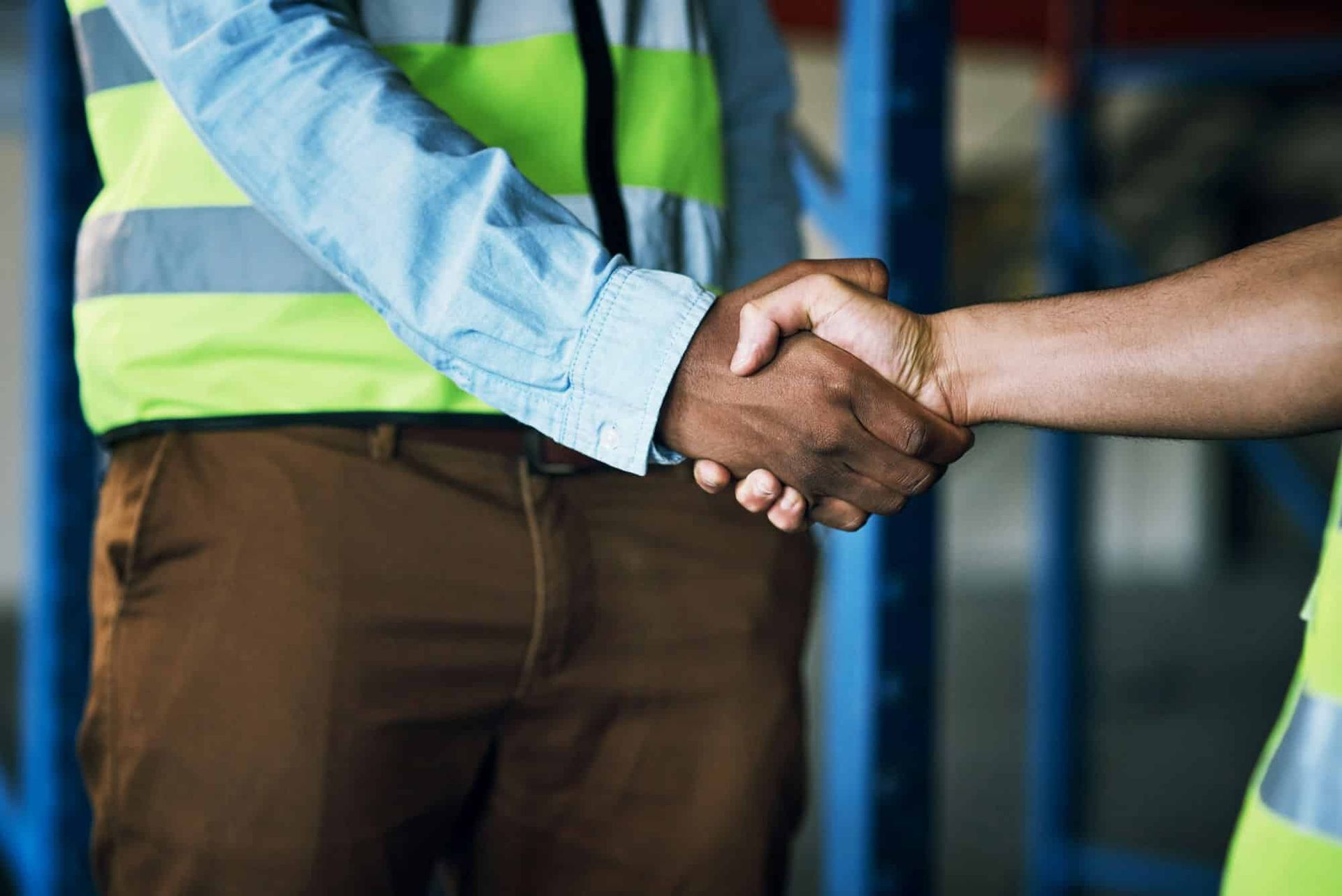 Two men are shaking hands in a warehouse.