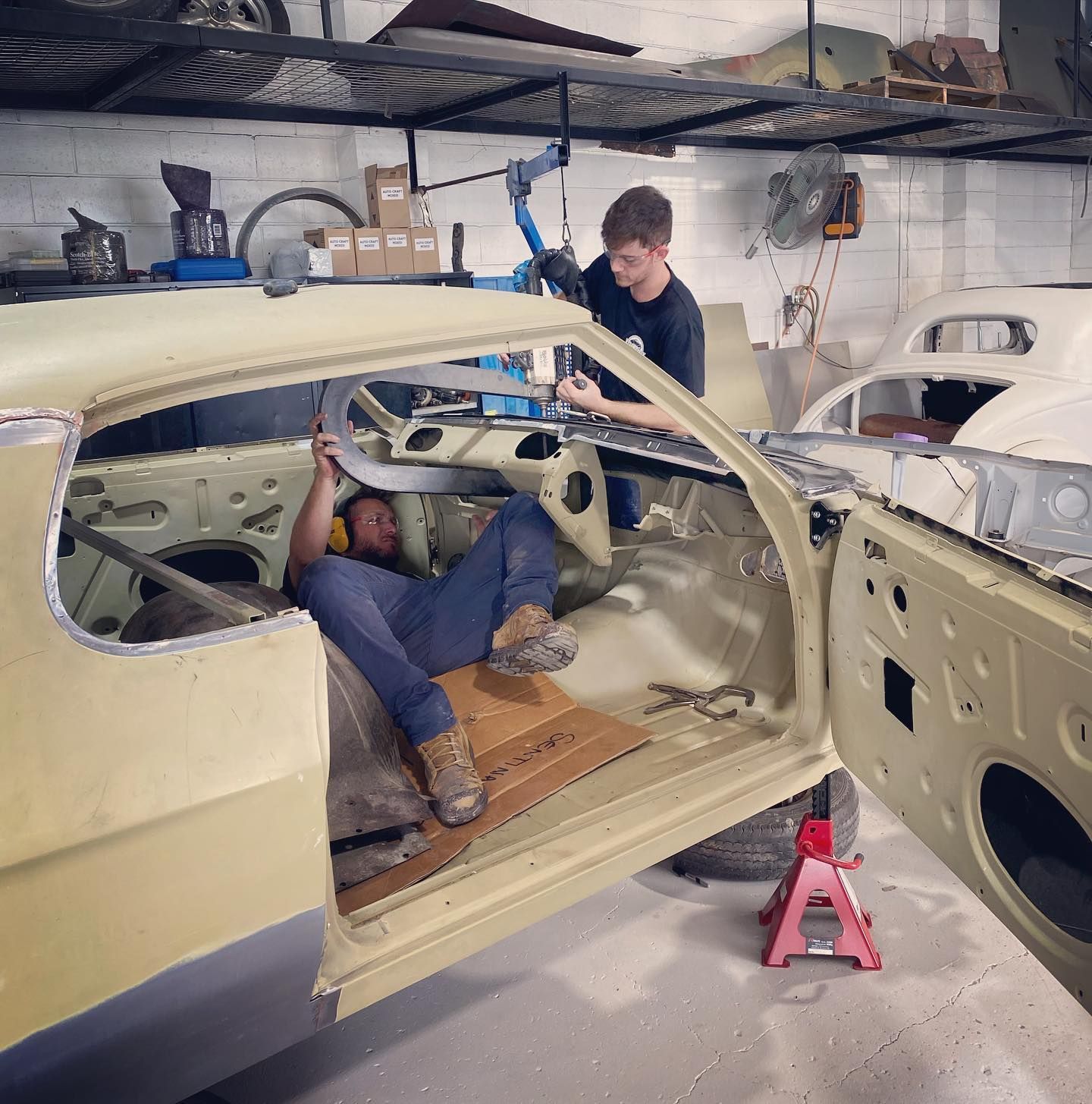 A Red Car is Parked in a Garage Next to a White Car — Auto Craft Collective in Rockhampton, QLD