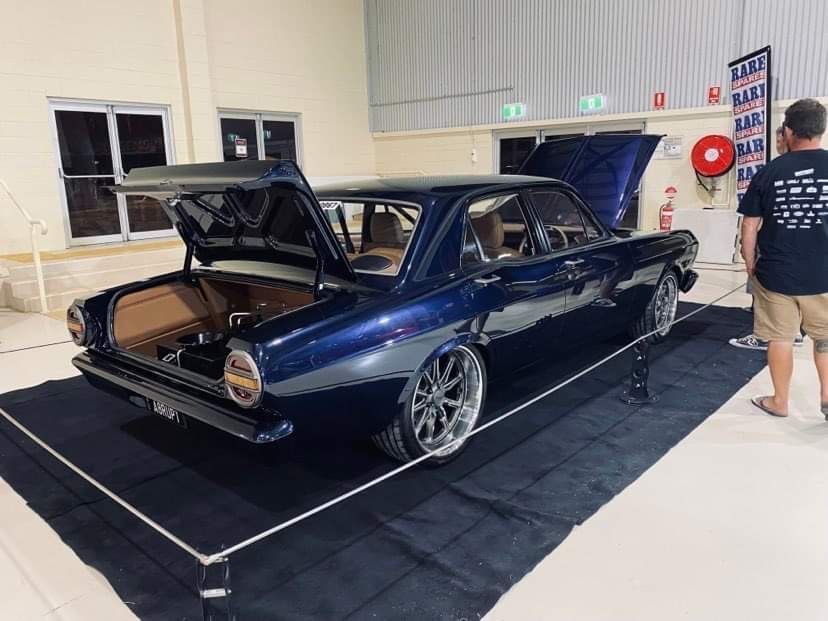 A Man is Standing Next to a Blue Car with the Trunk Open — Auto Craft Collective in Rockhampton, QLD