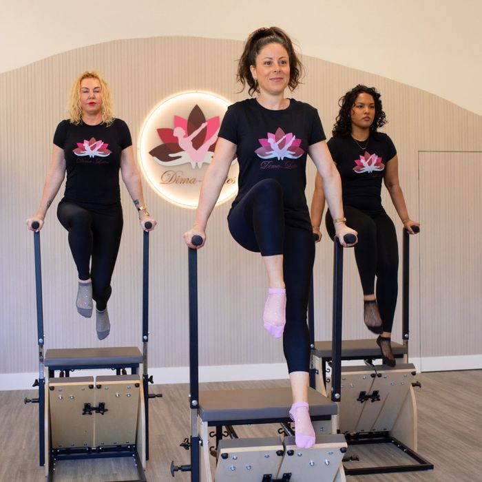 A group of women are doing a handstand in front of a pink wall