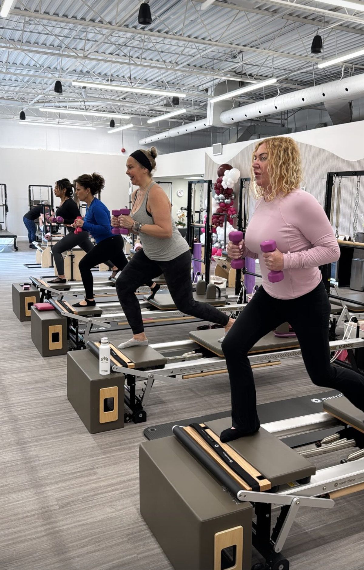 A group of women are doing exercises on pilates machines in a gym.