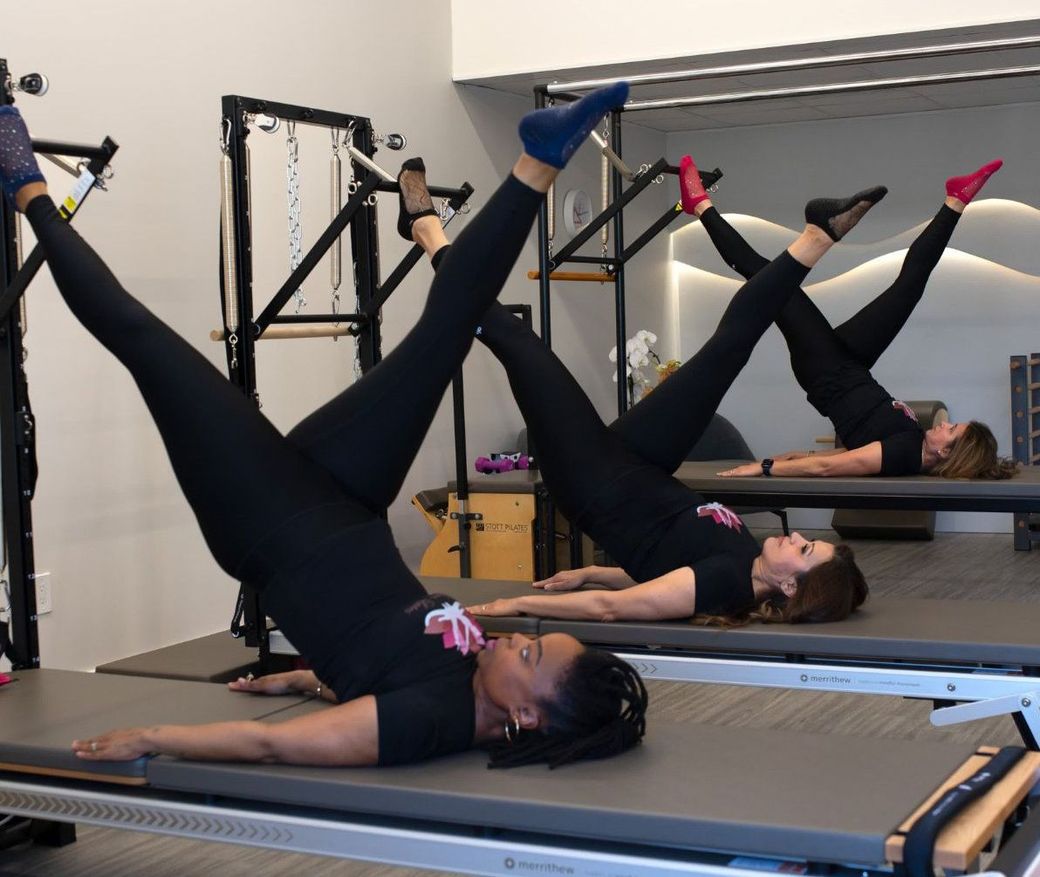 A group of women are doing push ups on pilates machines in a gym.