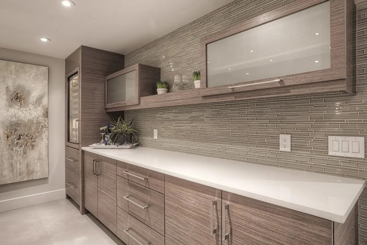 Modern kitchen with wood cabinets, white countertop, glass tile backsplash, and built-in wine storage.