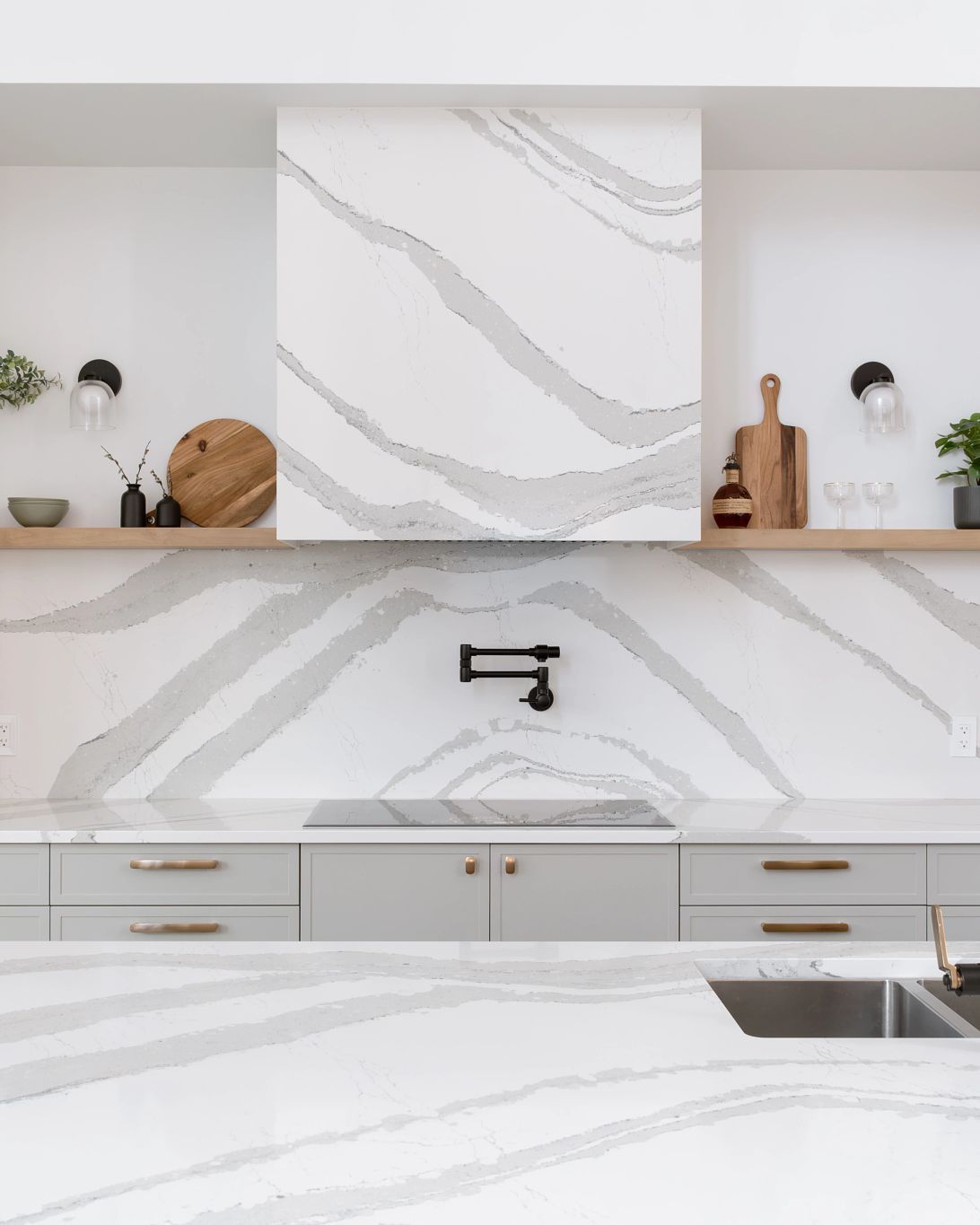 Modern kitchen with gray cabinets, quartz countertop, and patterned backsplash.