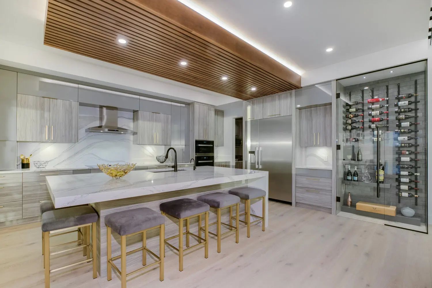 Modern kitchen with island seating, stainless steel appliances, and built-in wine rack.