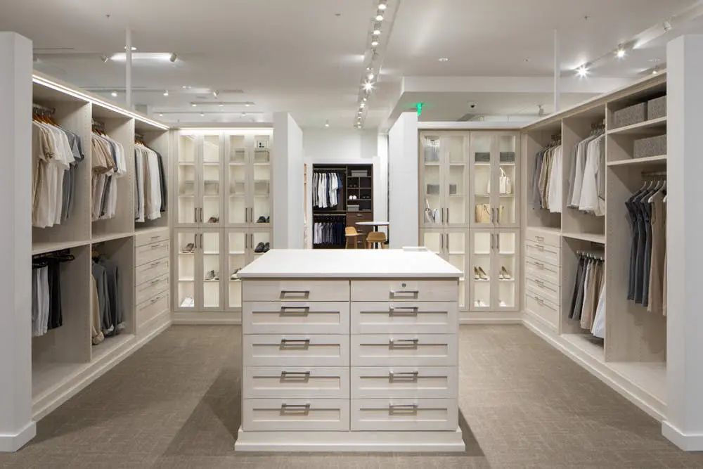 Spacious walk-in closet with white cabinetry, central drawers, and organized clothing.