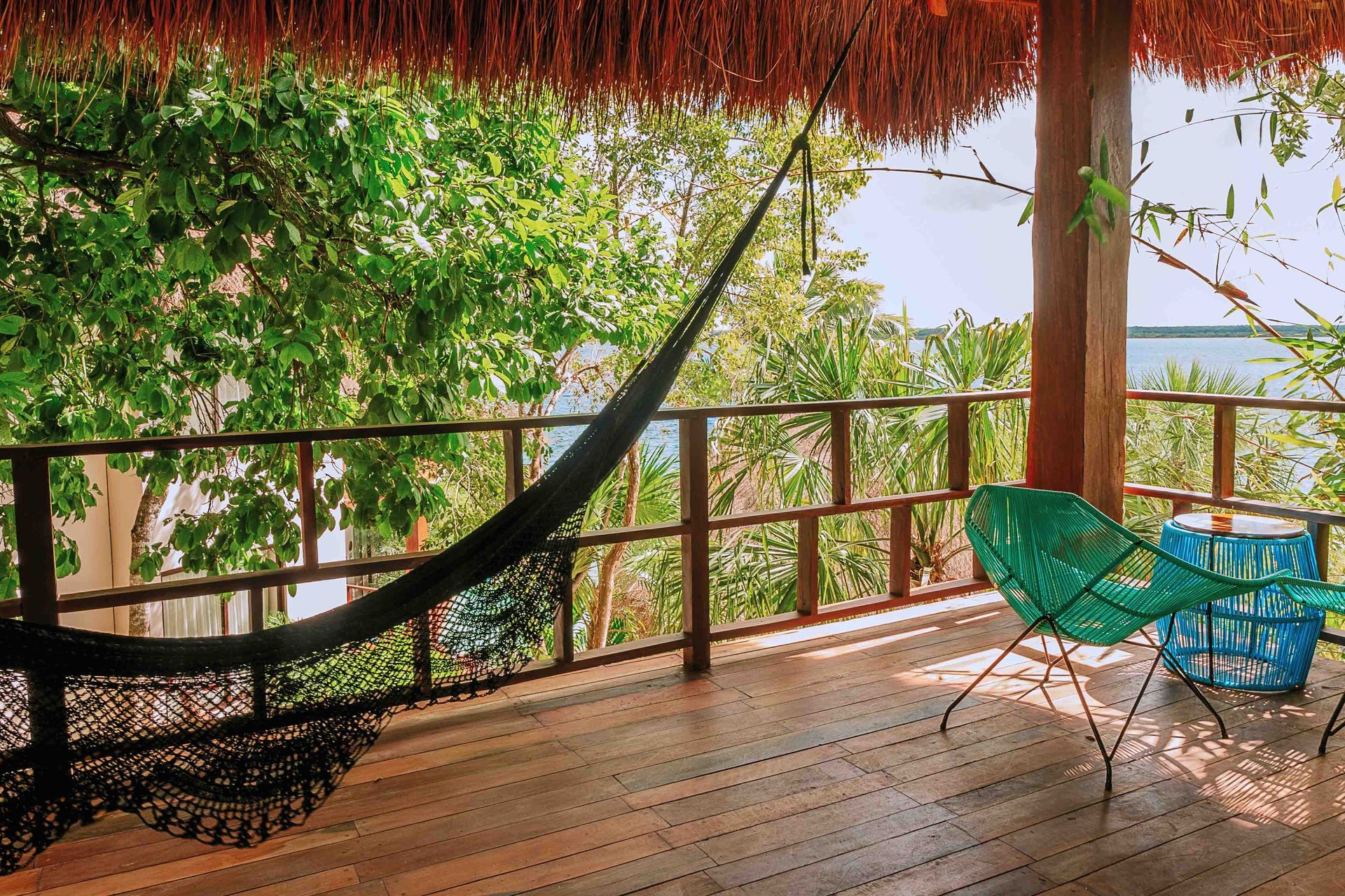 Una terraza de madera con una hamaca y sillas.