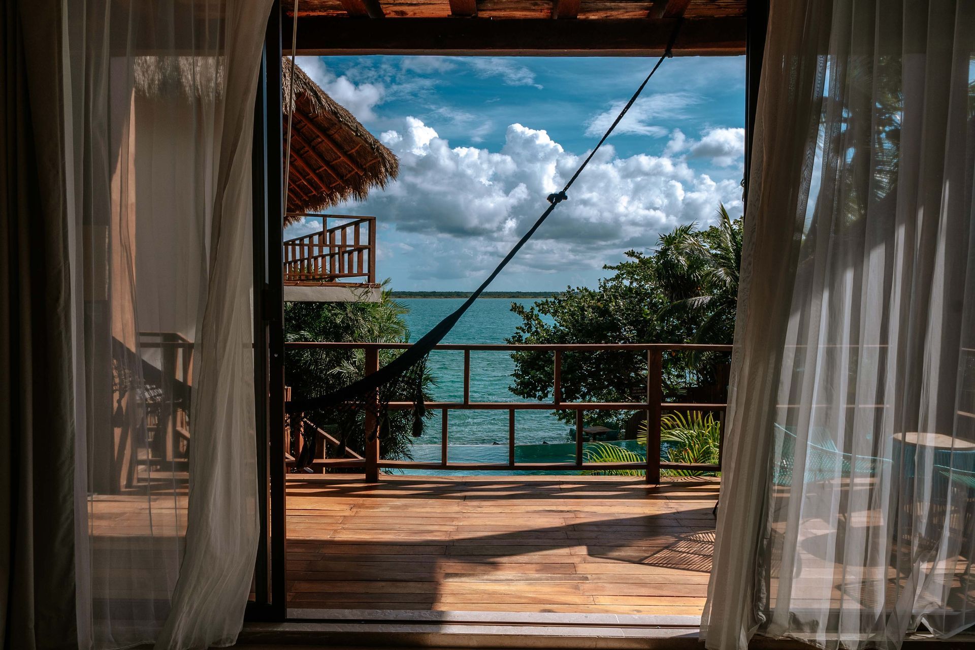 Hay una vista del océano a través de las cortinas de una habitación.