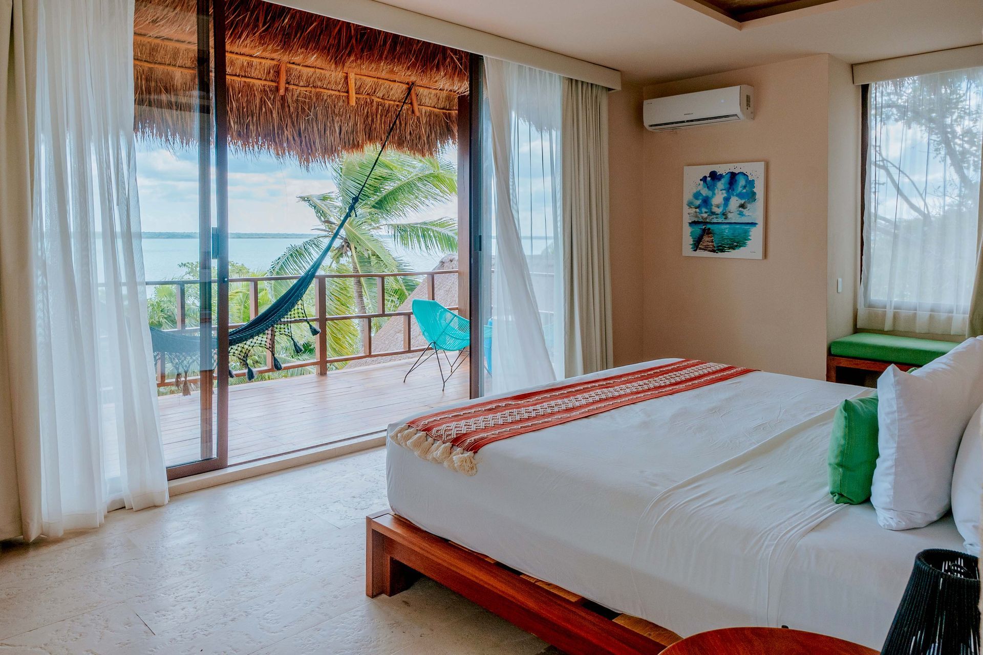 Una habitación de hotel con una cama, puertas corredizas de vidrio y una hamaca.