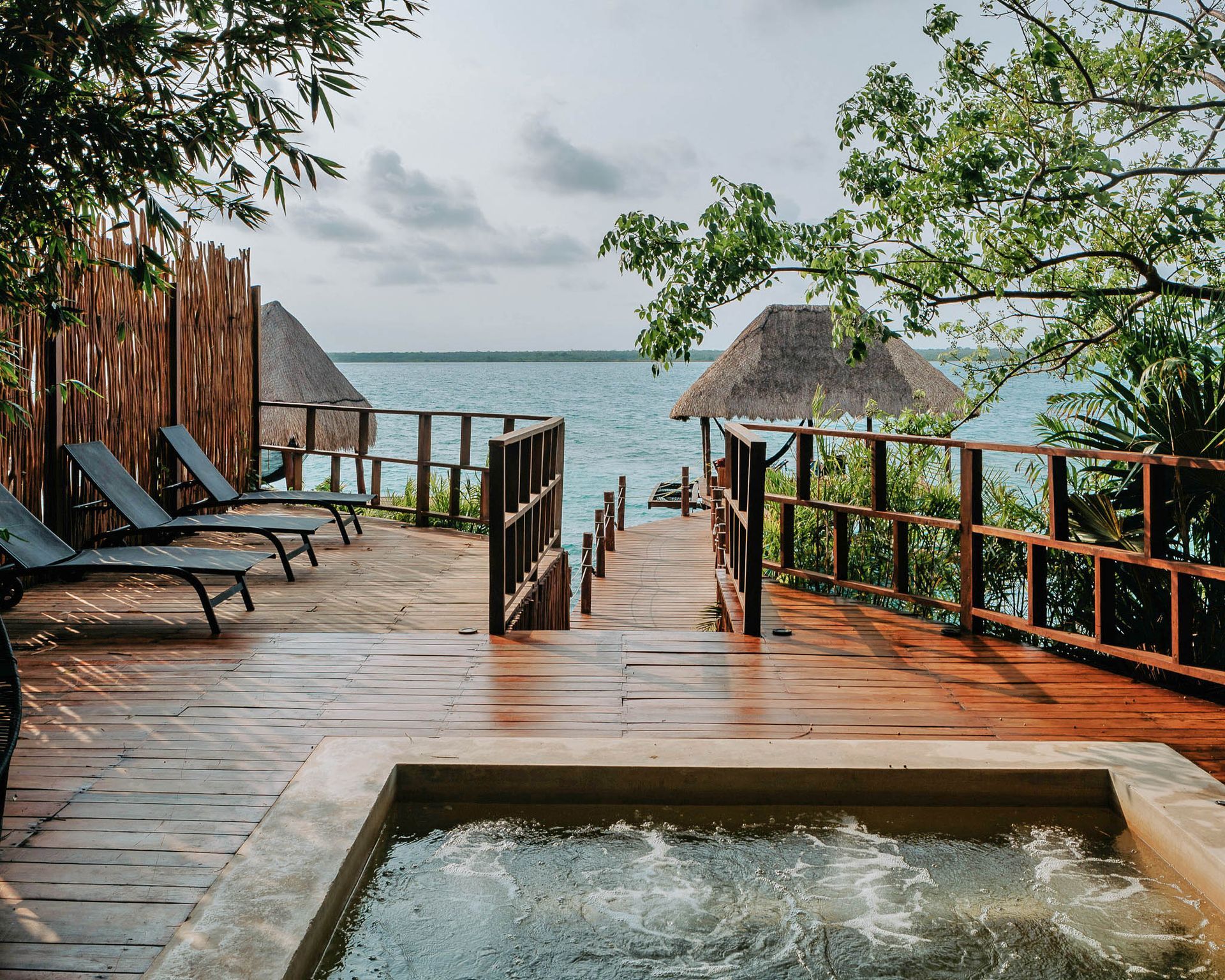 Un jacuzzi en una terraza de madera con vistas al océano.
