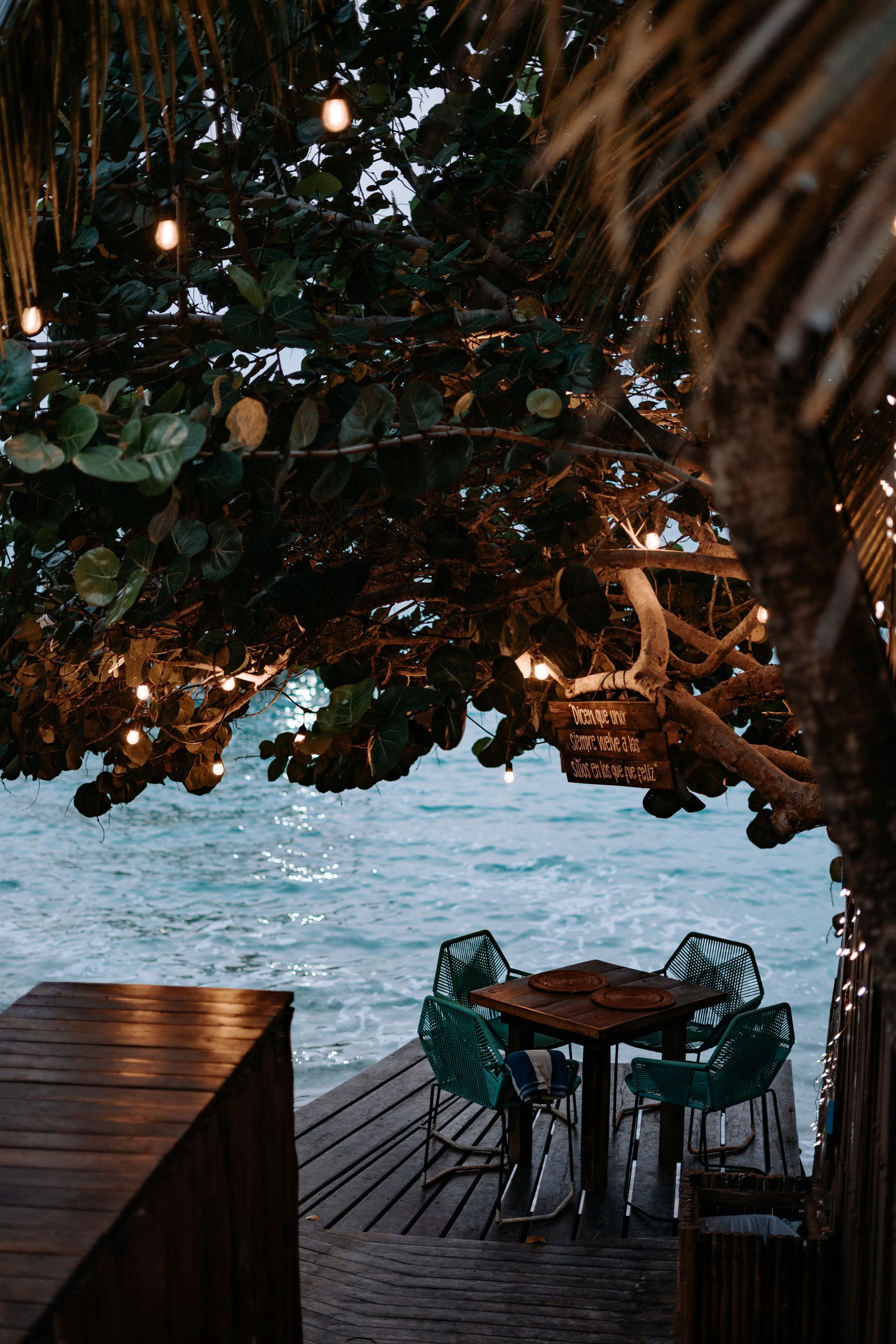 Una mesa y sillas en un muelle con vista al océano.