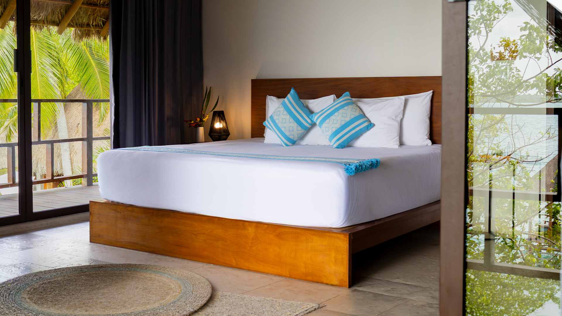 Upper-level guest room at Khaban Bacalar with a private terrace, natural light, and partial views of the palm trees.